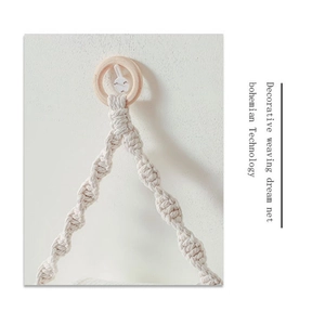 Close-up of bohemian hand-woven cotton macrame rope with natural wood ring on wall