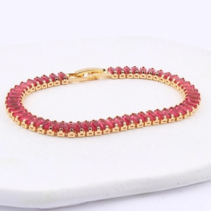 Macro shot of 18K gold tennis bracelet with emerald-cut deep red zircon crystals