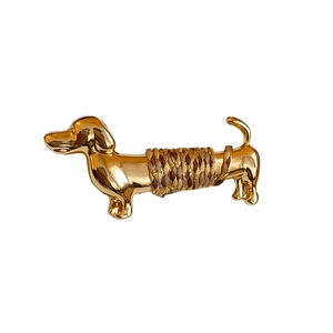 Broche teckel en métal doré avec cordelette tressée marron sur fond blanc pur