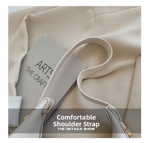 Detailed close-up of cream leather shoulder strap with gold metal buckle on a chic handbag