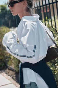 Detail of white long sleeve shirt featuring dark blue side stripes on sleeves in urban style