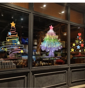 Detailed close-up of colorful Christmas tree window decals on a vintage glass storefront