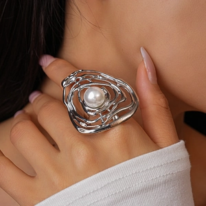 Macro detail of abstract liquid silver ring featuring a central white pearl on hand