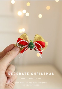 Gros plan de la pince à cheveux nœud de Noël rouge avec maille dorée et pendentif sapin