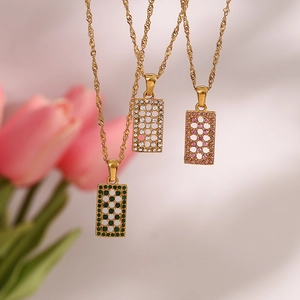Detailed view of rectangular geometric pendants with colorful zircon and gold chain