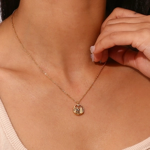 Macro view of gold chain necklace with intricate cutout city landscape tower pendant
