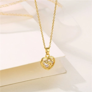 Collier cœur ajouré doré minimaliste avec pierre de zircon sur une page beige