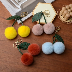 Detail of plush cherry keychains in multiple colors on a premium wooden surface