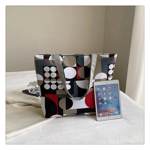 Detail view of large geometric print canvas tote bag next to a tablet for size reference