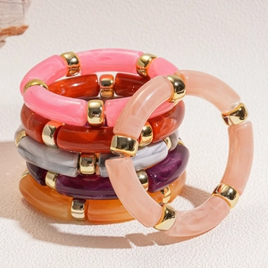 Detail view of colorful acrylic bamboo tube bracelets with golden metal spacer beads