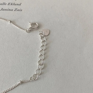 Macro shot of 925 sterling silver lobster clasp with heart charm and extension chain
