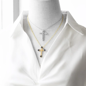 Close-up of gold cross necklace with blue gems and silver cross with clear stones