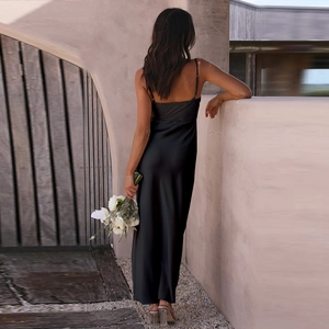 Elegant back view of black satin slip dress with slit and thin straps in outdoor light