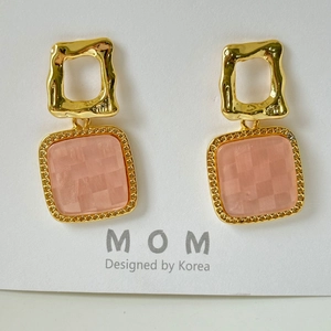 Macro view of gold-plated square earrings featuring a pink checkerboard resin inlay