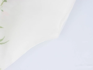 Détail du tissu organza blanc avec imprimé délicat de feuilles vertes et texture fine