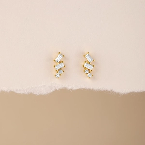 Macro detail of gold sterling silver stud earrings featuring geometric clear crystals