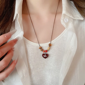 Détail d'un collier de perles avec pendentif cœur rouge et emblème d'orbite en métal