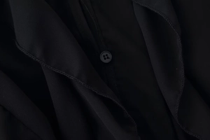 Detail of a black V-neck shirt featuring twill fabric texture and a matte button closure