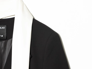 Gros plan du revers contrasté et de l'épaule sur un blazer tissé noir de qualité