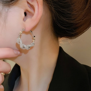 Macro shot of silver twisted hoop earring with textured chain design on a model