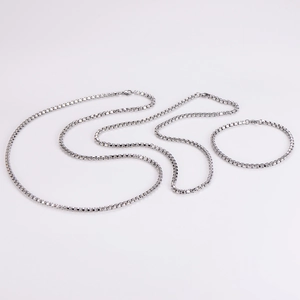 Flat lay of square pearl box chain necklace and bracelet set in polished silver steel