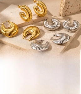 Detailed macro view of textured croissant hoop earrings in gold and steel finish