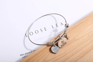 Détail du bracelet extensible en acier avec breloque dorée mi mama et pendentif cœur argent