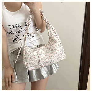 Detail of floral underarm bag with pleated scrunchie strap and side bow design