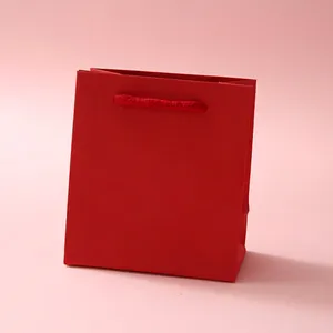 Detailed view of a premium red paper gift bag with matching woven handles and matte finish