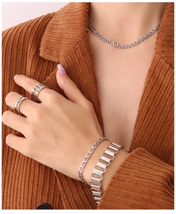 Close-up of silver chain necklace and bracelets set on brown corduroy jacket