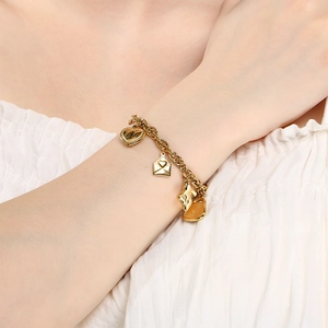 Detail of 18K gold charm bracelet with heart lock and bear pendants on a female wrist