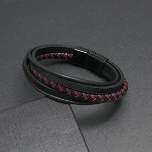 Macro detail of multi-layer black and red braided leather bracelet with magnetic buckle