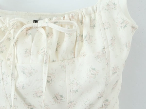 Dettaglio dello scollo con coulisse e stampa floreale sulla trama tessuta di questo top