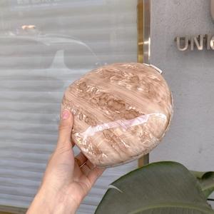 Detail of egg-shaped marble pattern clutch bag held in hand for dinner party use