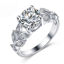 Macro detail of silver ring with round main stone and leaf-shaped side diamond settings