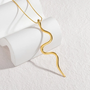 Detail of creative snake pendant on fine chain with gold-plated finish and smooth texture
