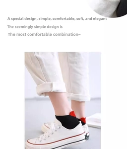 Detail of low cut cotton socks in black and red paired with white canvas shoes