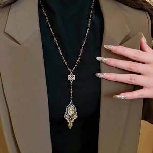 Detail of vintage beaded necklace with oval teardrop pendant on a brown suit outfit