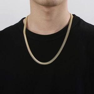 Macro shot of wide gold snake chain necklace featuring polished flat herringbone links