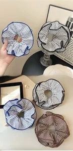 Close-up of striped fabric scrunchies in blue and brown with pleated edge detail