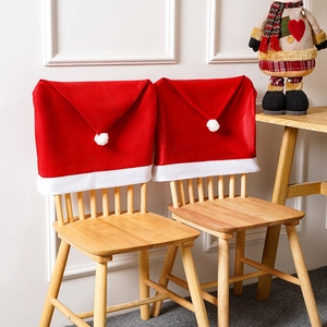 Red and white Christmas Santa hat chair covers with pompoms for holiday dining decor
