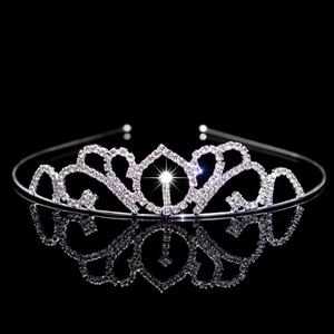 Close-up of sparkling rhinestone crown on black reflective surface with elegant reflection