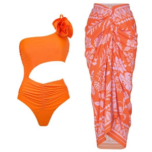Detail of orange one-shoulder swimsuit with 3D flower and tropical print sarong