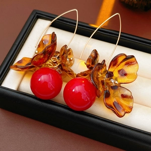 Detail of red bead earrings with amber floral charms and gold hooks on display