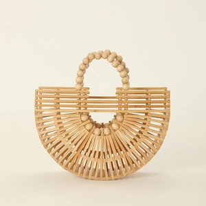 Detail of a natural bamboo handbag featuring openwork weaving and a wood bead handle