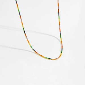 Macro detail of rainbow tennis necklace with colorful gemstones and gold chain