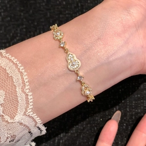 Détail d'un bracelet gourde plaqué or 18 carats avec perles et strass sur un poignet