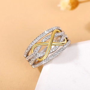 Macro detail of infinity ring with gold-tone cross band and sparkling white micro-zirconia