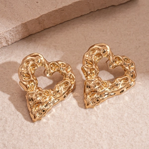 Close-up of golden heart earrings featuring artistic lava texture and irregular hollow design