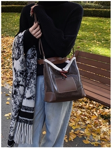 Detail of vintage coffee leather bag with white faux fur trim and red horn button toggle